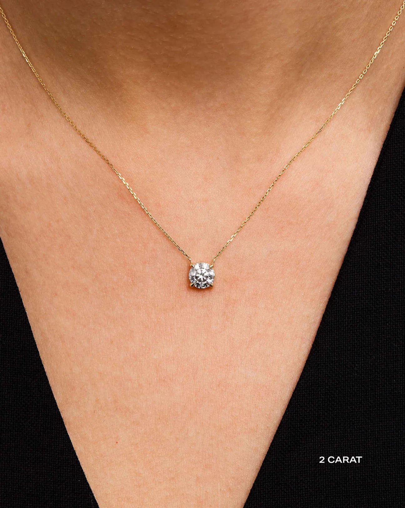 14kt hallmark yellow Gold chain necklace with a 2 ct lab diamond pendant on a person's neck.
