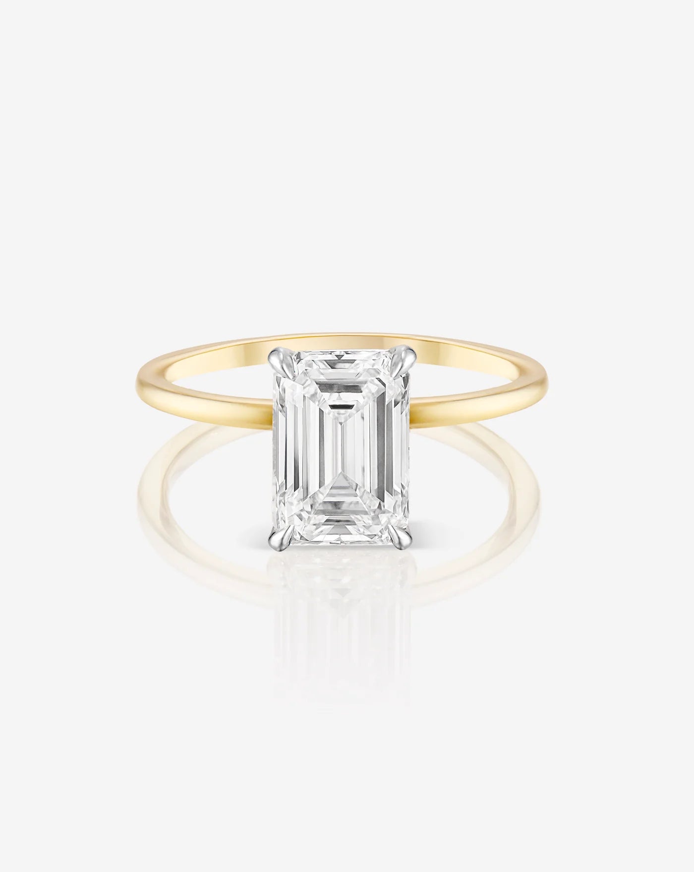 The image shows the 2 carat emerald cut diamond solitaire ring in a hallmark 14kt yellow gold band from the front, showcasing the exceptional cut of the diamond.