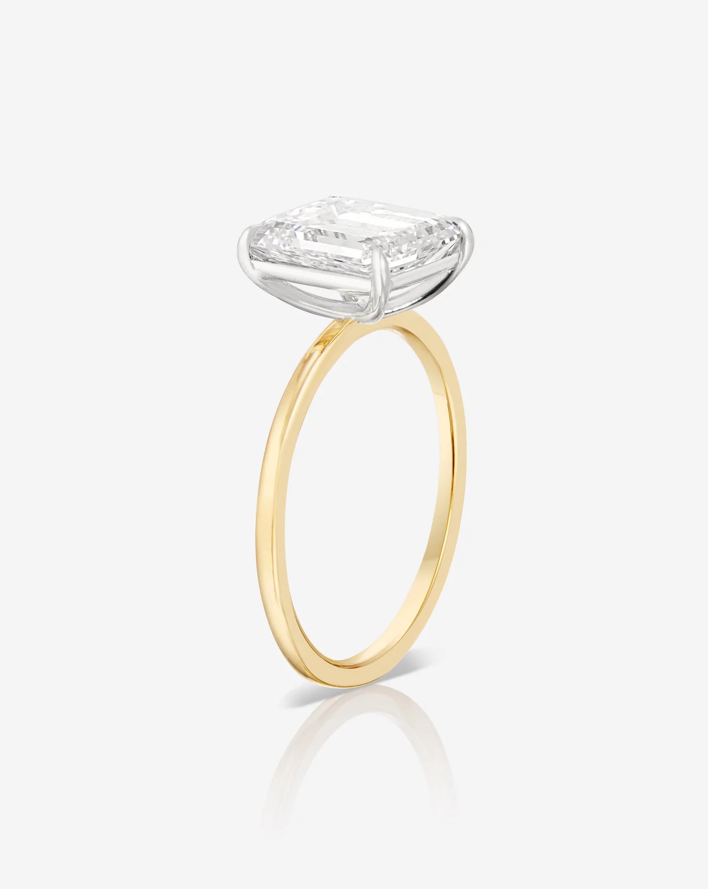 2 carat emerald diamond solitaire ring in a yellow gold band, showing the prong setting from the side