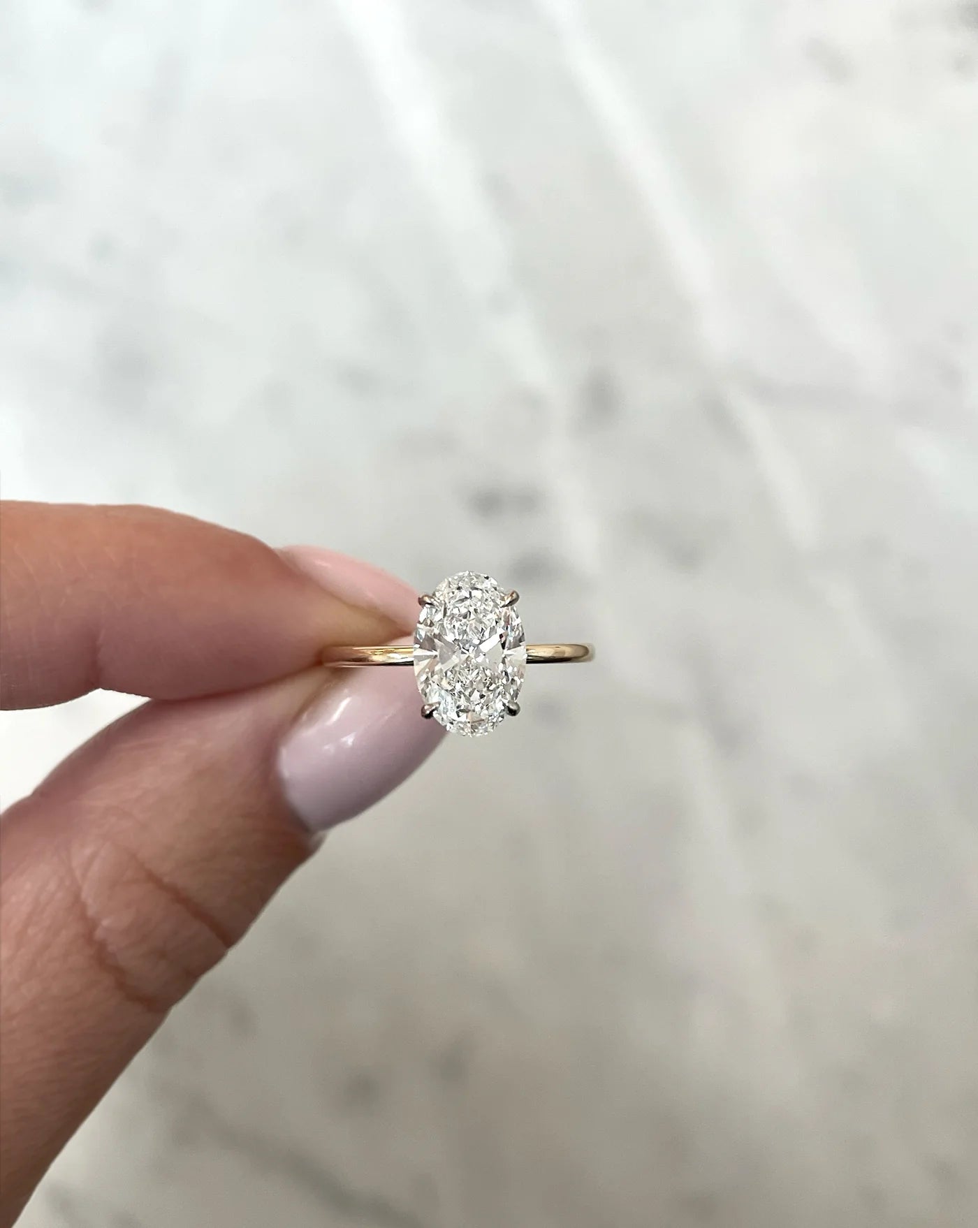 2 carat oval lab diamond solitaire ring in 14kt hallmark yellow gold band, set with 4 prongs. The image shows the cut and clarity of the diamond from the front.