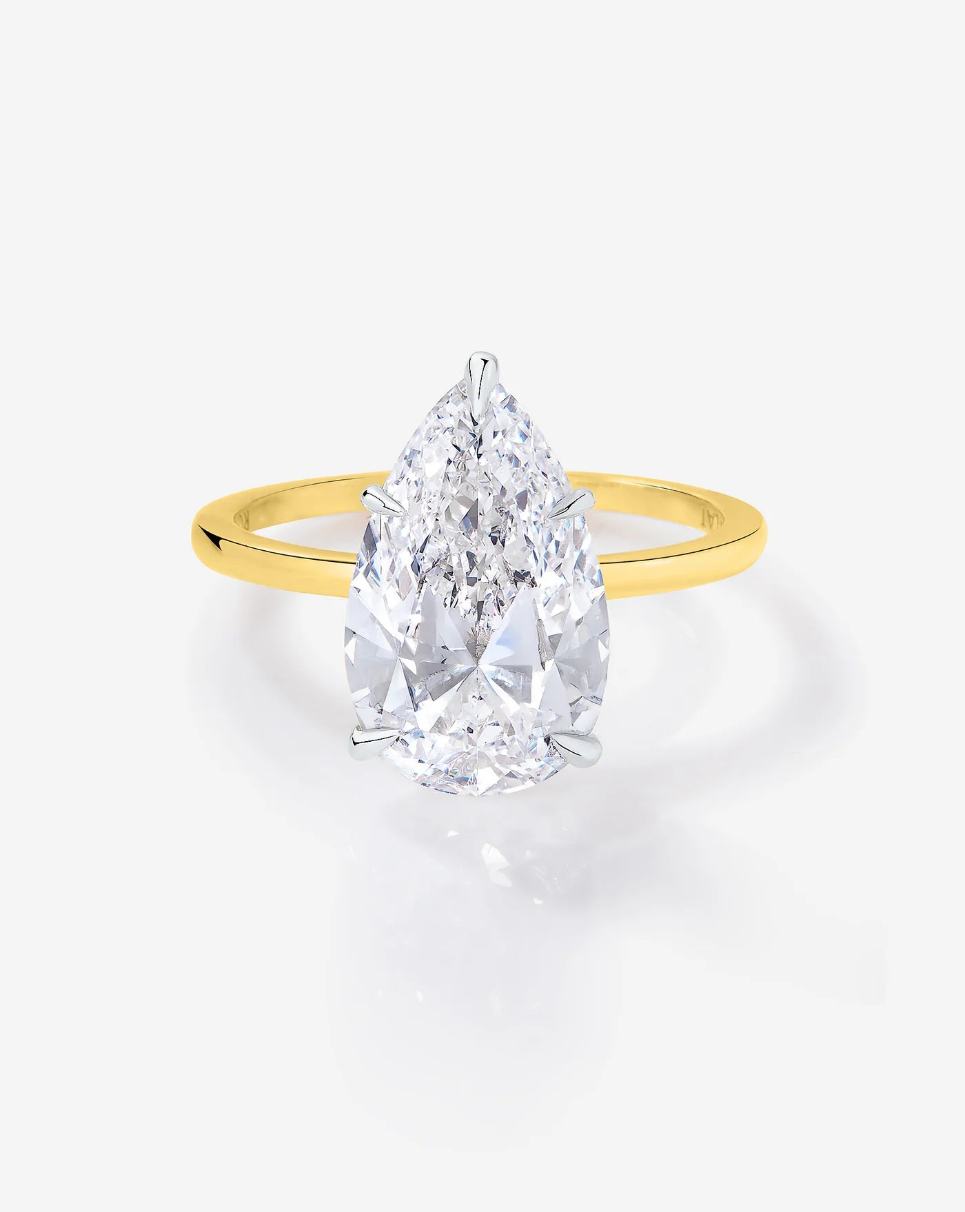 The image shows a close up of a pear shaped diamond ring showing its cut and clarity set in a sleek gold band.