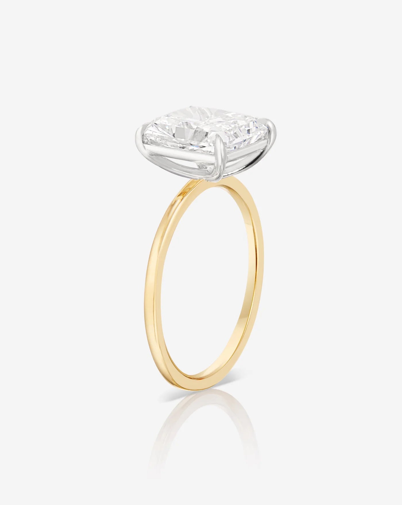The image shows an angular view of the sleek yellow gold band, holding a diamond