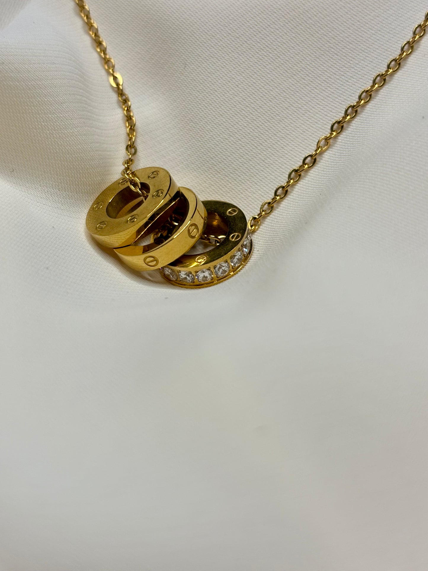 Close up of the pendant showing 3 rings, 2 with circle design and one with moissanite stones made in Sterling silver and gold plating