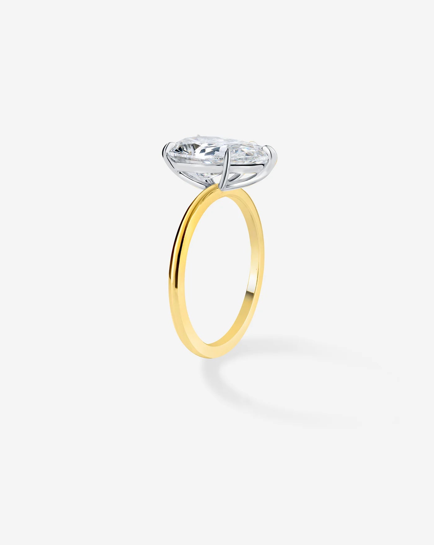 The image shows a side view of a sleek gold band, holding a pear shaped diamond.