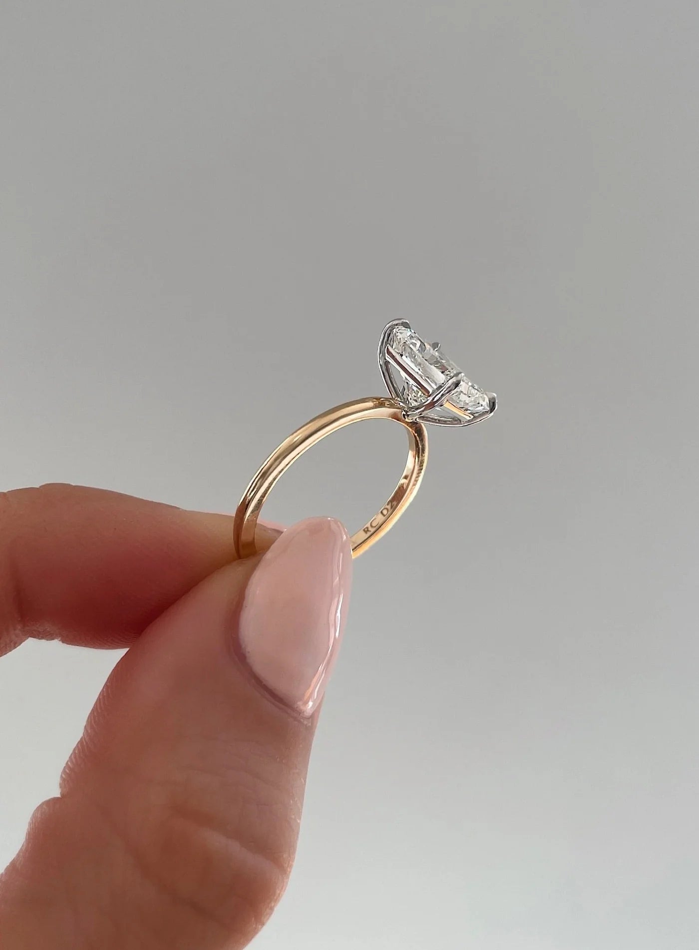 The image shows the sleek yellow gold band and classic prong setting of the diamond ring