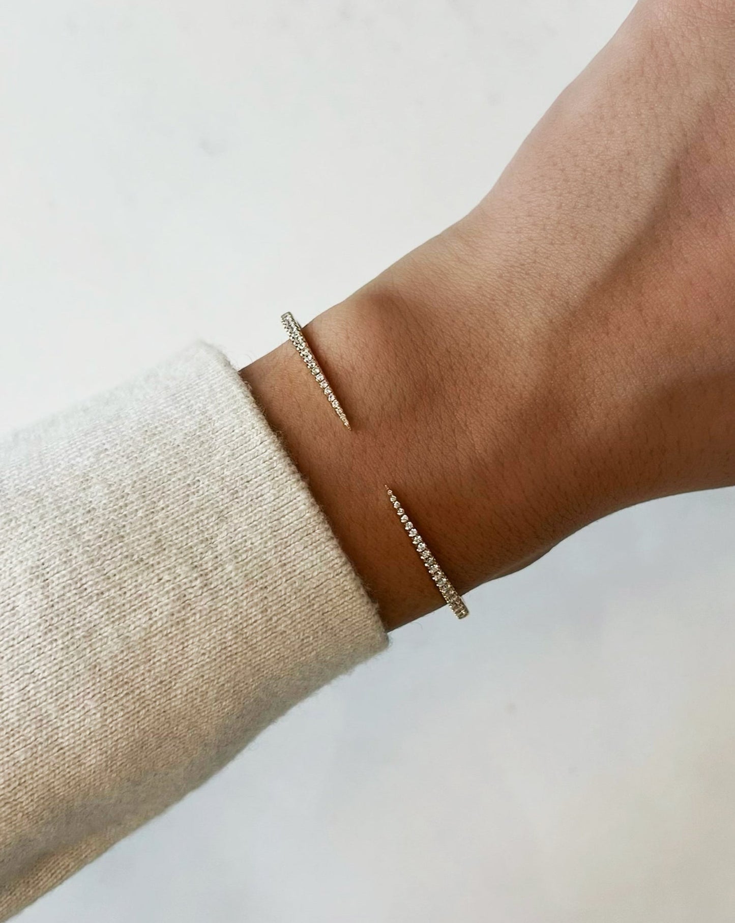 Image shows a hand wearing the delicate claw bracelet featuring 42 diamonds and made in hallmark 14kt yellow gold