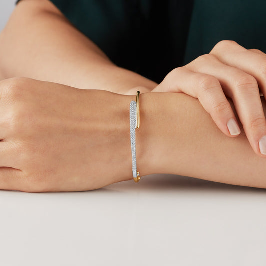 14kt hallmark yellow gold and diamond pave bangle on a hand.
