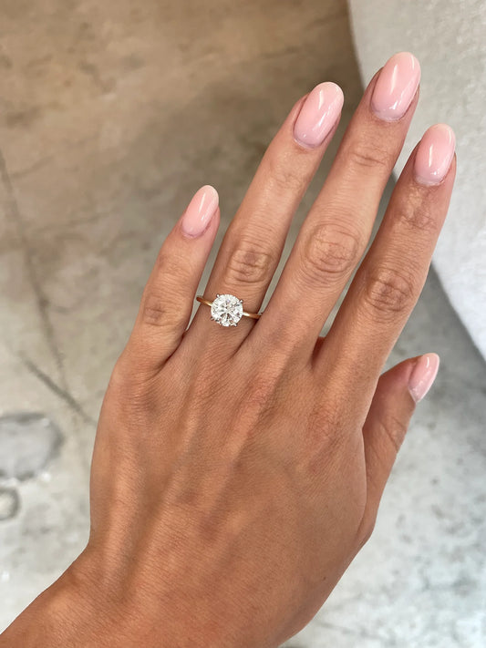 2 carat round lab diamond solitaire ring in 14kt yellow gold band set with 4 prongs. The image shows how the ring looks when adorned.