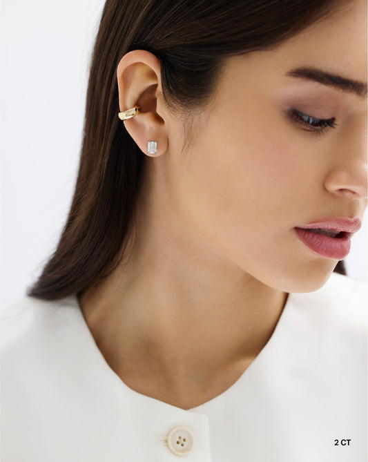 The image shows a close up of a woman wearing a 2carat emerald cut diamond star earring set in 14 carat hallmark White Gold