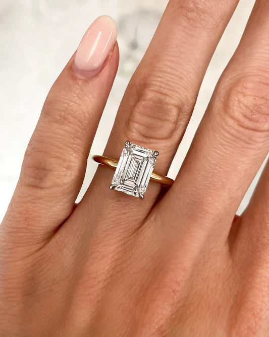 3.4 CT emerald cut lab diamond ring in 14kt yellow gold band. Elegant solitaire design with four-prong gold setting.