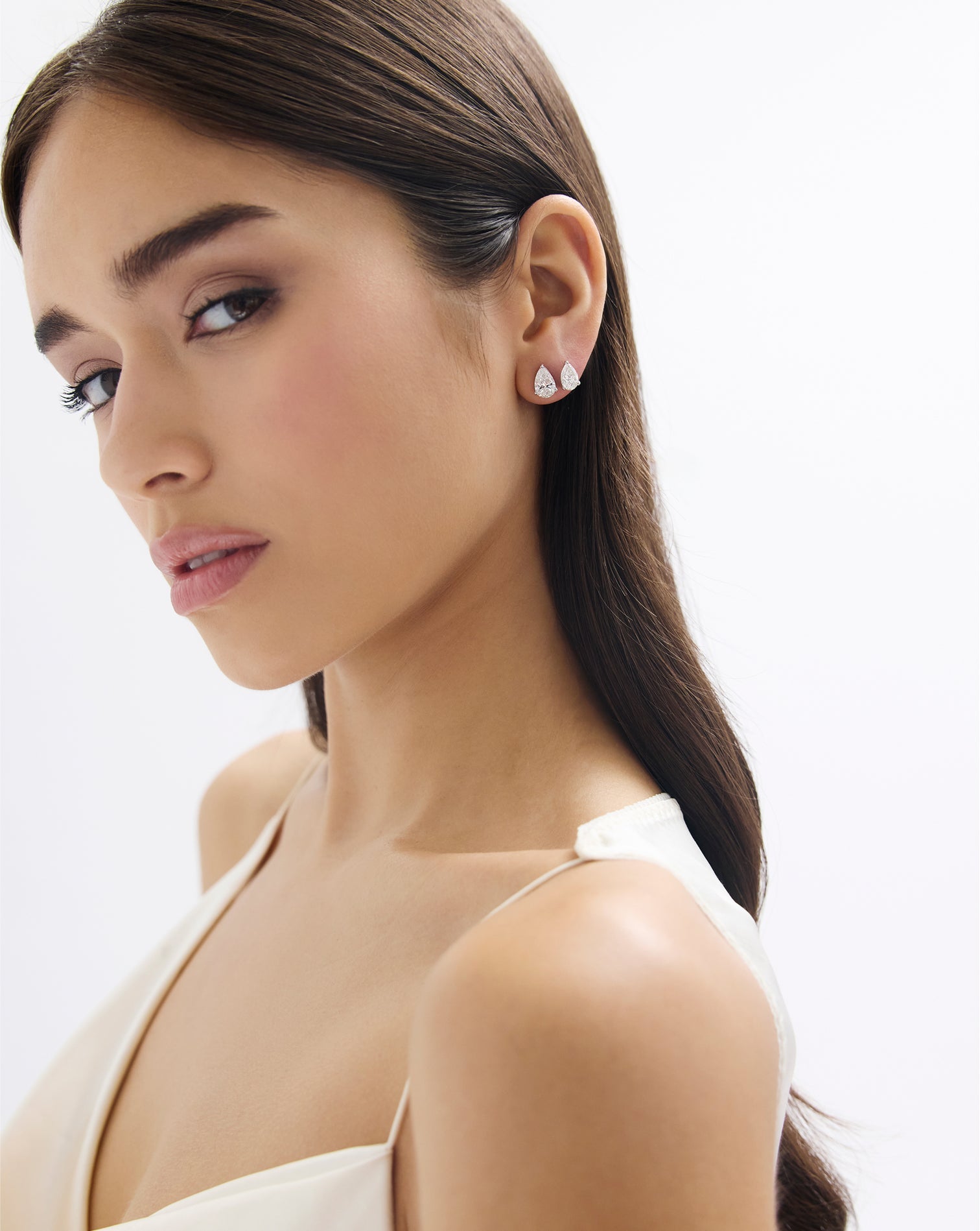 Close up of a 3 ct pear shape lab diamond stud earring in 14kt hallmark white gold. The image showcases how the earrings enhance the look when adorned.