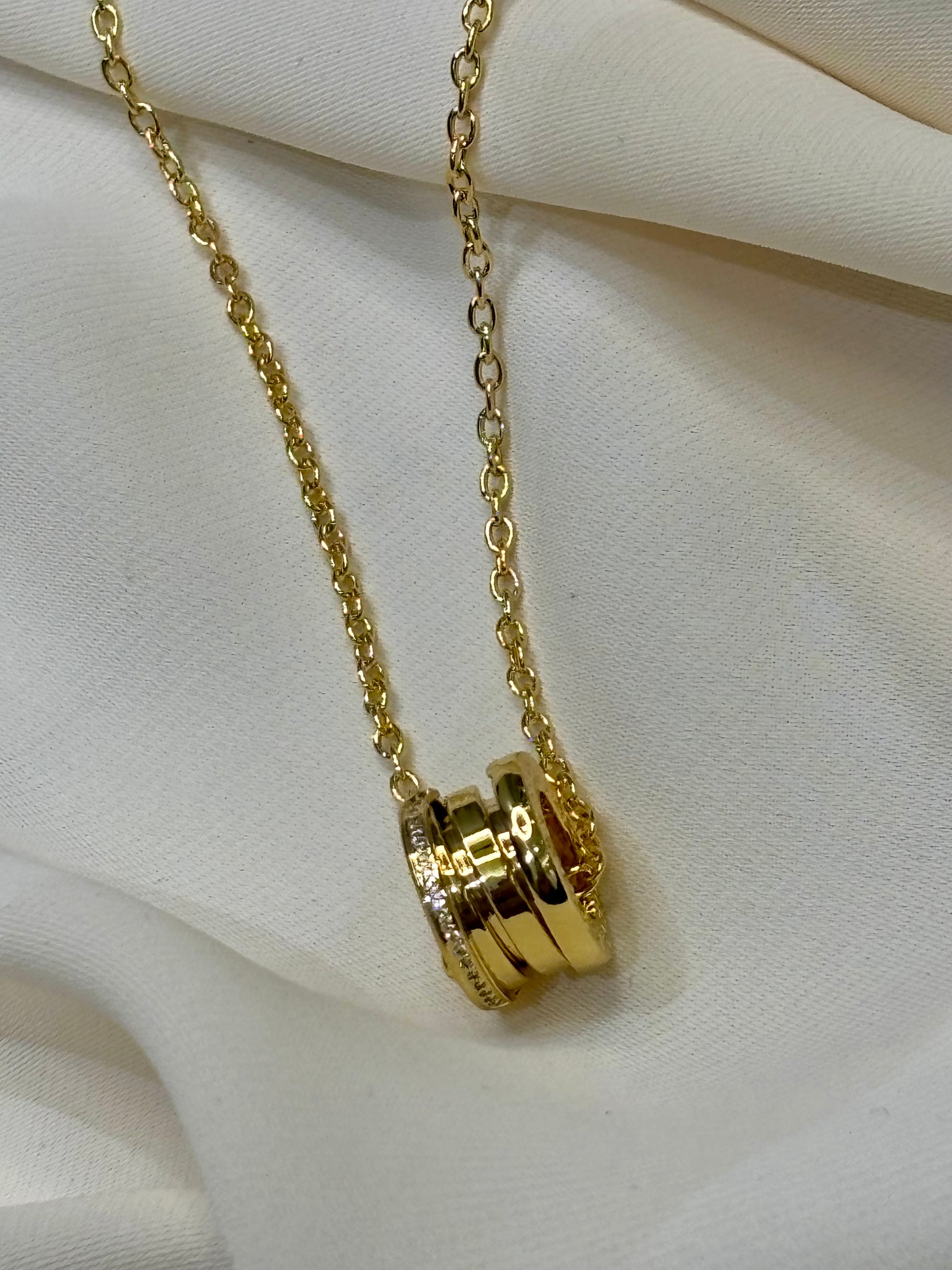 A circular pendant with moissanite pave setting on sides made with 92.5 Sterling silver with 18kt gold plating in a gold tone chain