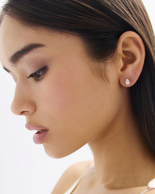 Woman wearing half carat pear shape diamond stud in white gold