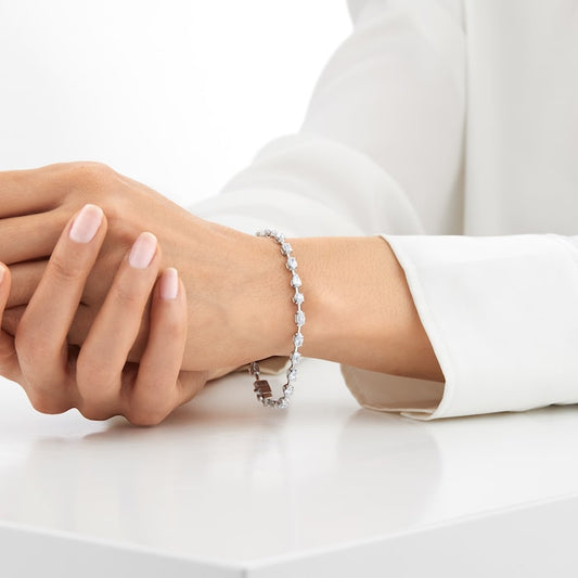 Close up of a hand wearing a mixed shape lab diamond tennis bracelet in 14kt hallmark white gold, weighing 5.98 carats.