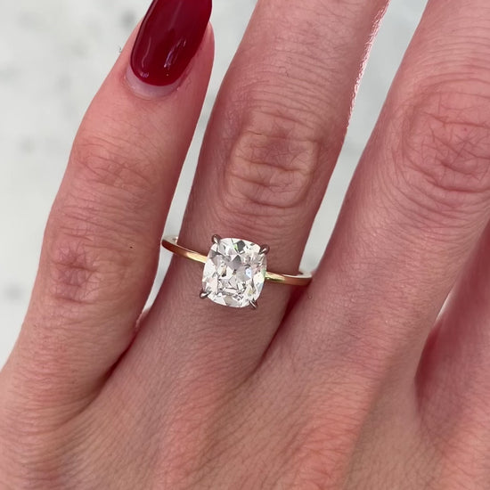 1.50 carat cushion cut lab diamond solitaire ring in 14kt hallmark gold band on a hand in movement.