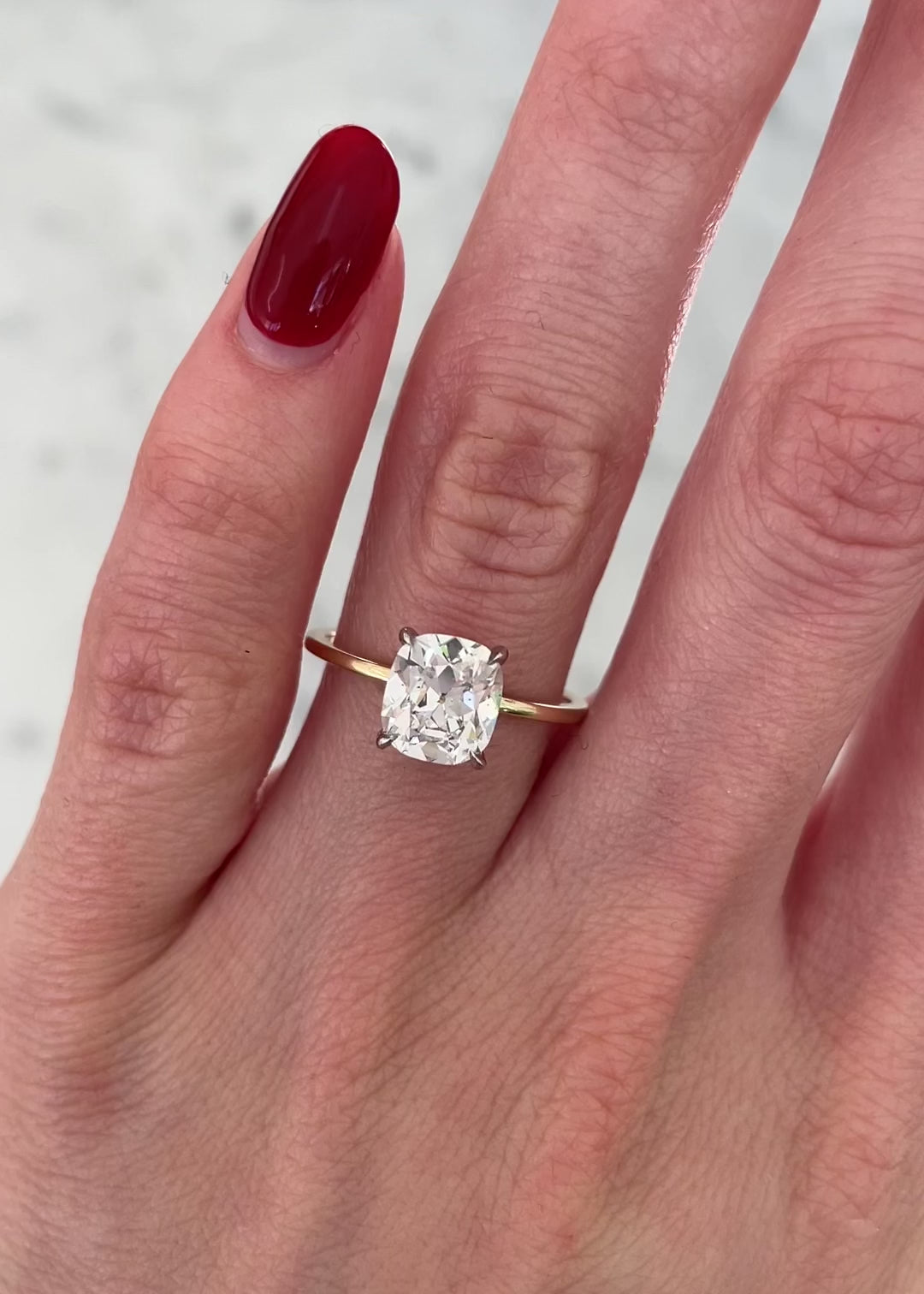 1.50 carat cushion cut lab diamond solitaire ring in 14kt hallmark gold band on a hand in movement.