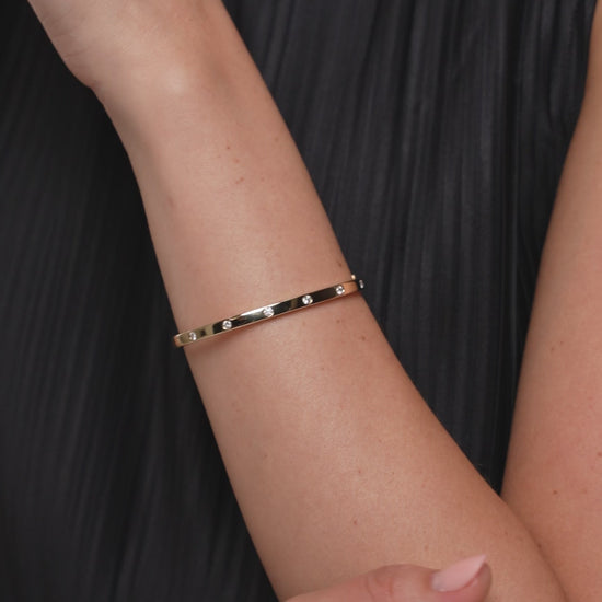 Video shows a complete view of a diamond inlay bangle. The bangle is made in 9kt yellow gold with lab diamonds.
