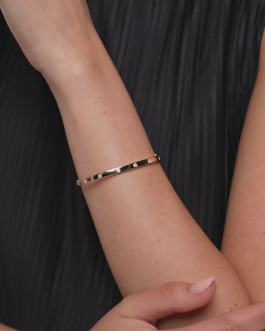 Video shows a complete view of a diamond inlay bangle. The bangle is made in 9kt yellow gold with lab diamonds.