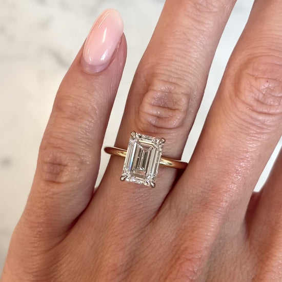 3.4 ct emerald cut lab diamond ring set in 14kt yellow gold band. Elegant solitaire setting with 4 gold prongs.