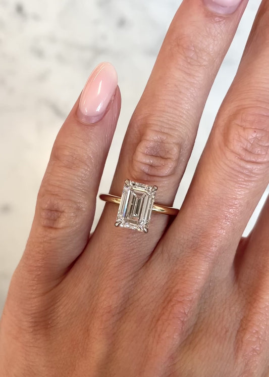 3.4 ct emerald cut lab diamond ring set in 14kt yellow gold band. Elegant solitaire setting with 4 gold prongs.